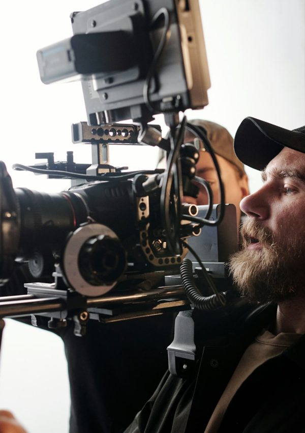 Side view of bearded cameraman in casualwear standing in front of camera